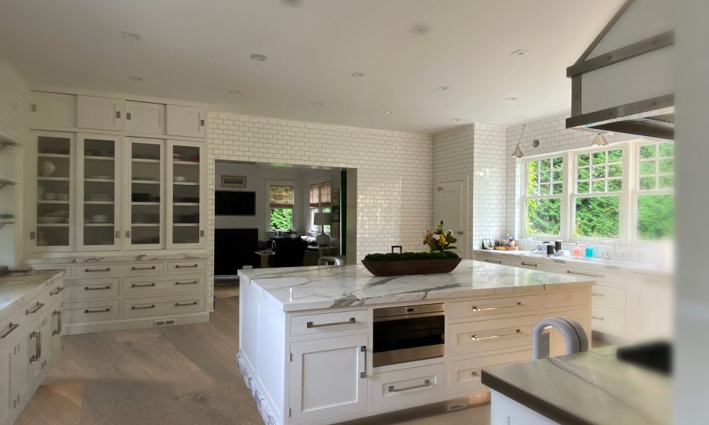 White farmhouse style kitchen with glossy brickwork and large expansive cabinets