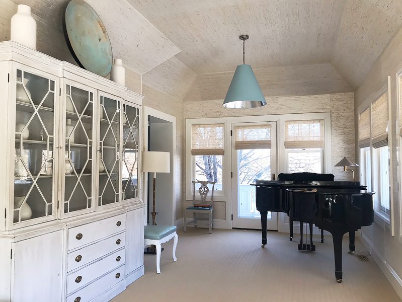 Sunroom with piano and modern farmhouse aesthetic on woodgrain walls and cabinetry.