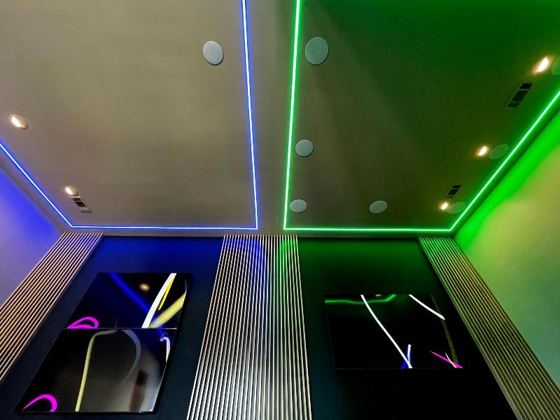 Linear and canvas LEDs joining together a single room with vertical acoustical panels in an entertainment room.