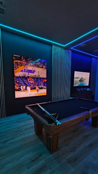 Fully completed game room replete with vertical acoustical panels linear lighting and Samsung TV displays with sports and a pool table Elite AV and Lighting.