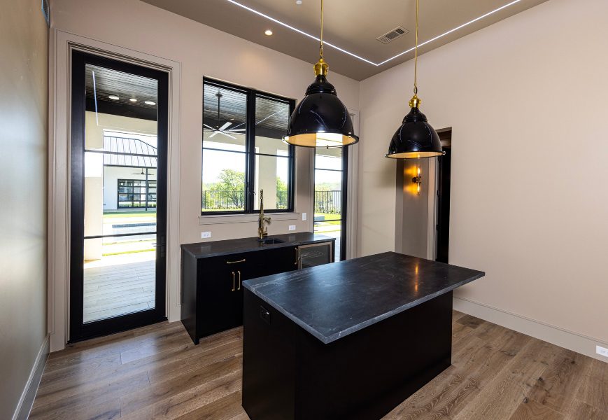 Black onyx lighting pendants with black marble counters in custom home looking out onto outdoor area.