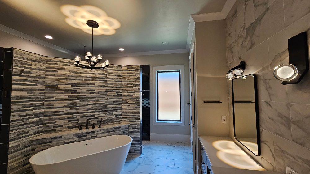 Modern bathroom setting with overhead chandelier and spotlights over the counter