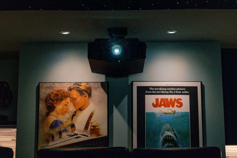 Titanic and Jaws movies posters beneath projector with light turned on in home theater Fusion Audio Video